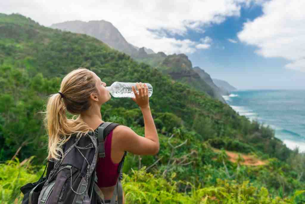 A girl drinking water while hiking in mountains
