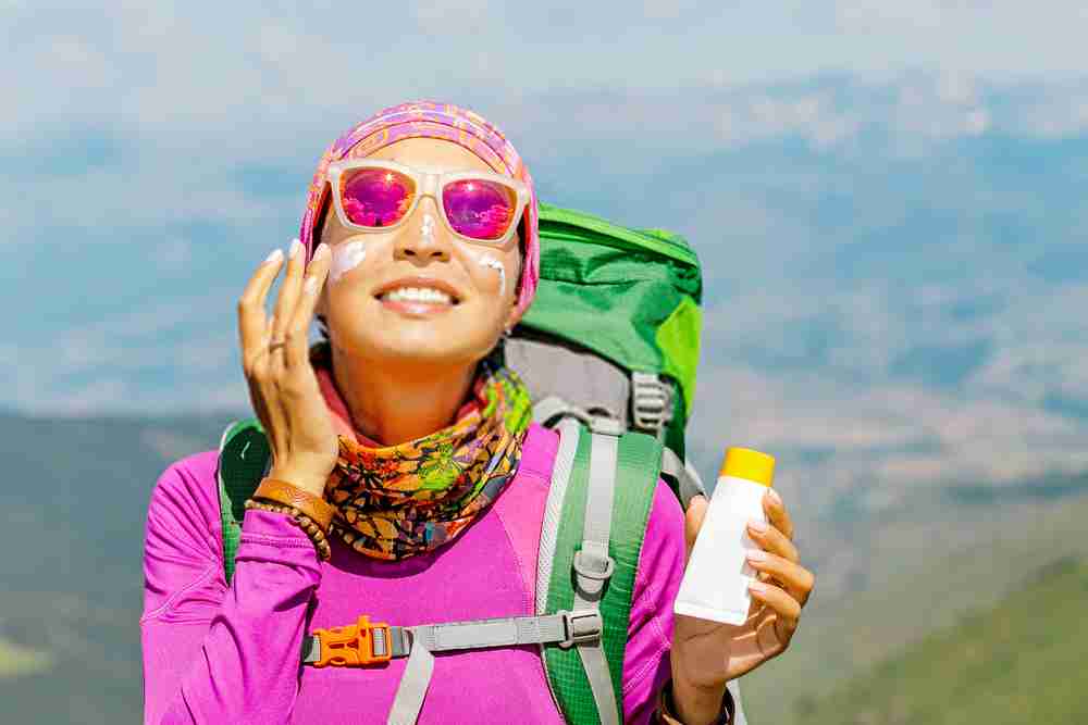 Applying sunscreen girl hiker for sun protection on sunny weather